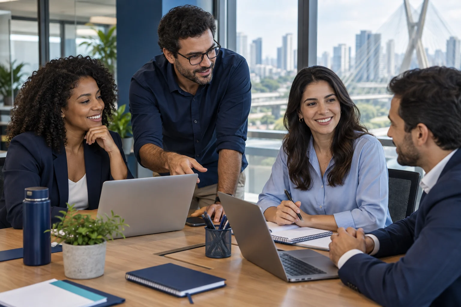 Profissionais reunidos em uma mesa de trabalho com computadores.